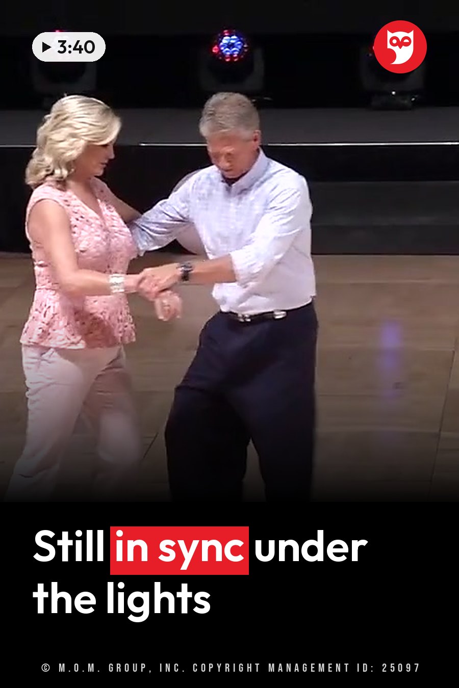 A man and a woman dance together on a wooden floor under stage lights. A headline runs in white letters across the lower third.