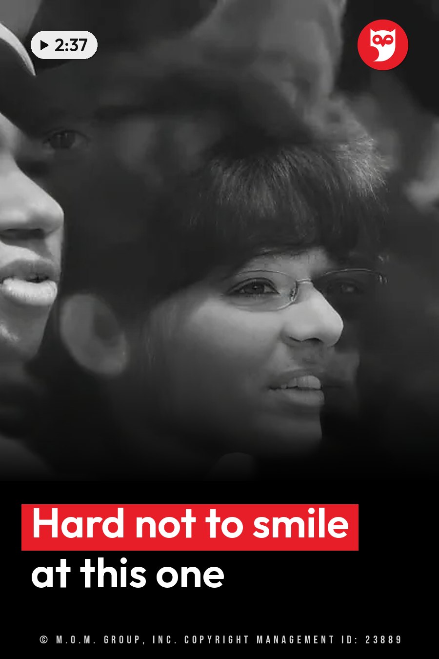 A woman with glasses smiles while standing next to another person who is partly out of view. A headline runs in white letters across the lower third.