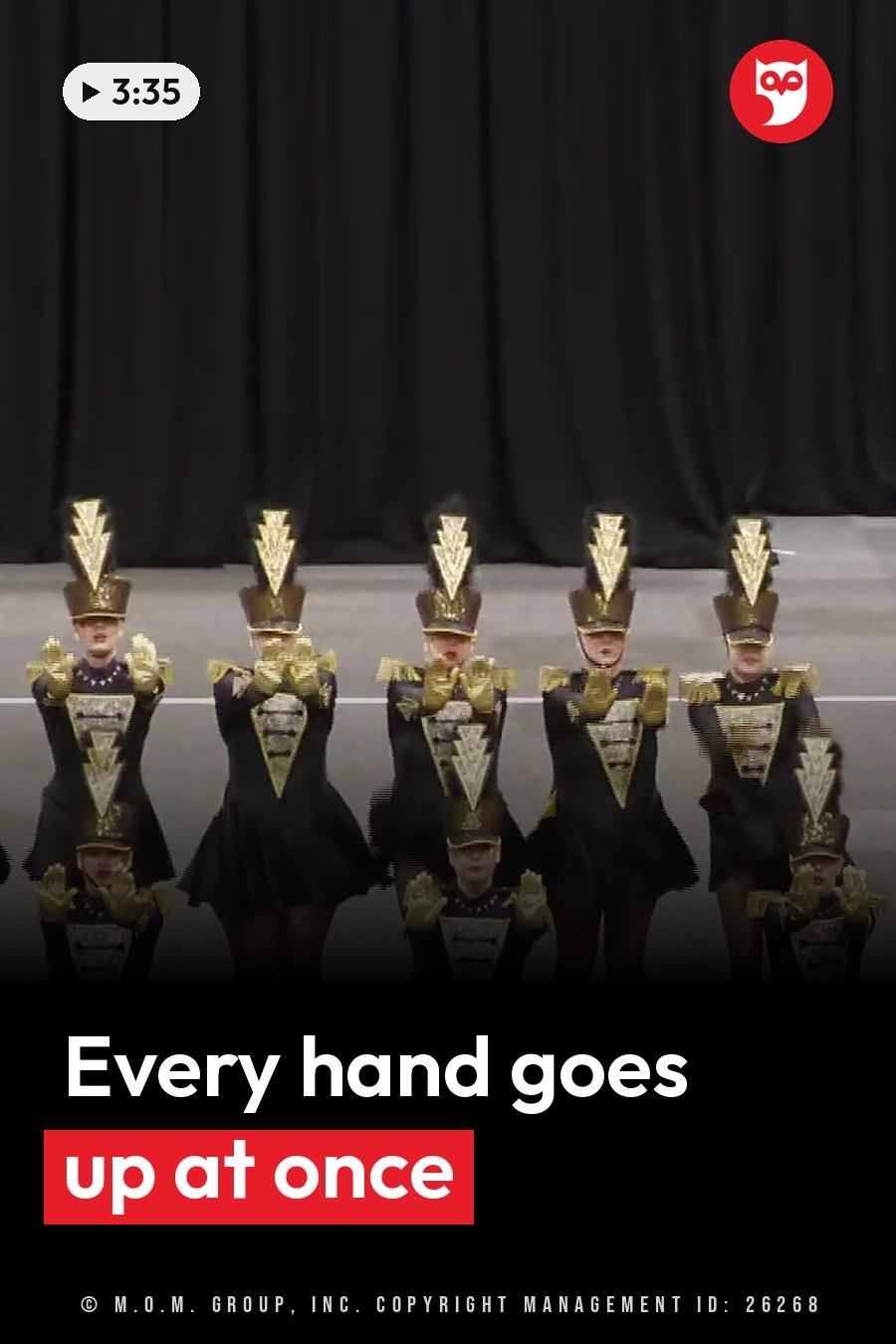 Six performers in black and gold uniforms stand on a stage facing forward with their hands raised. A headline runs in white letters across the lower third.
