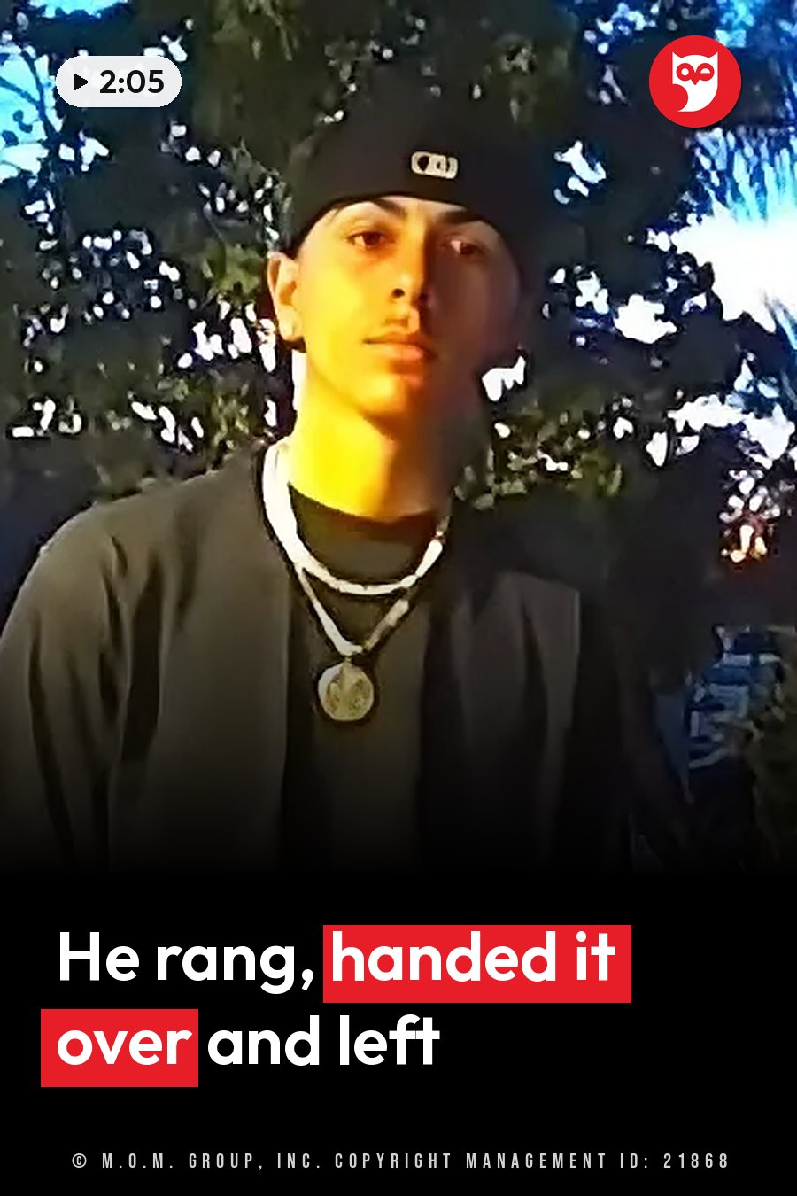 A person in a cap and a necklace stands outdoors at night with trees behind them. A headline runs in white letters across the lower third.