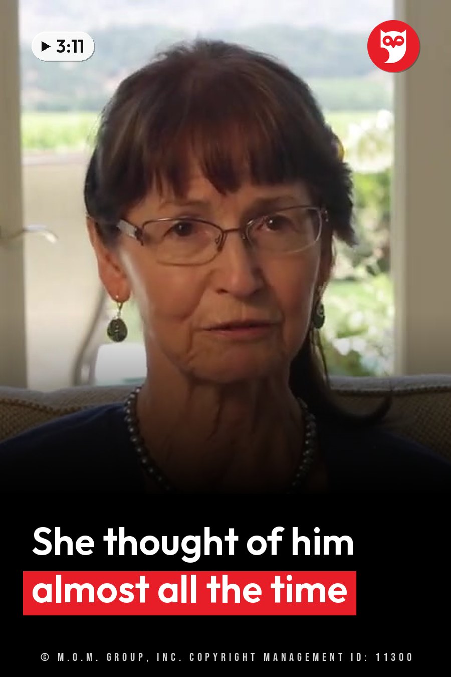 An older woman with glasses, earrings and a necklace sits indoors and looks ahead. A headline runs in white letters across the lower third.