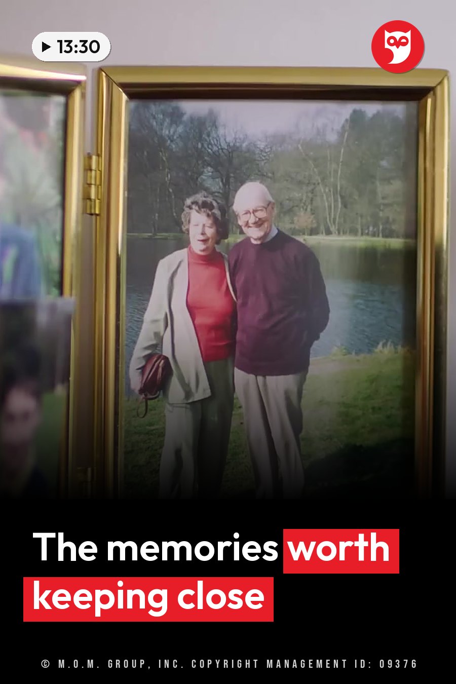 An elderly couple stands smiling beside a lake, holding hands near the water's edge, with trees around them. A headline runs in white letters across the lower third.