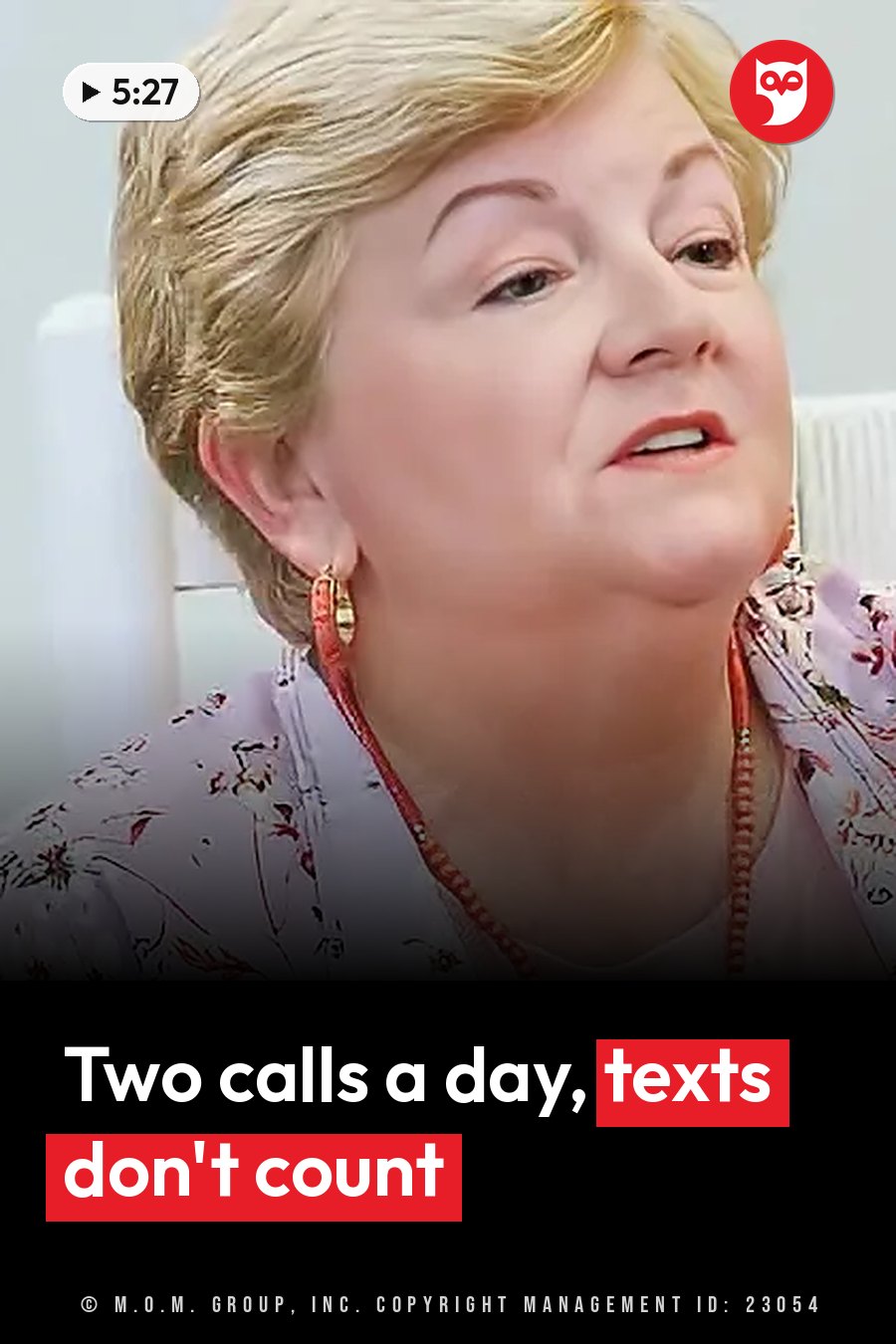 A woman with short blonde hair, in floral clothing and red jewelry, looks upward as she speaks. A headline runs in white letters across the lower third.