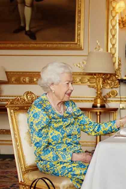 Opulent room with ornate gold-framed chairs, framed paintings on walls, and chandeliers at Buckingham Palace during daytime with natural light.