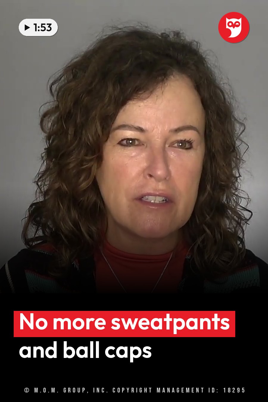 A woman with curly brown hair, wearing a red shirt and a patterned sweater, looks ahead while she speaks. A headline runs in white letters across the lower third.