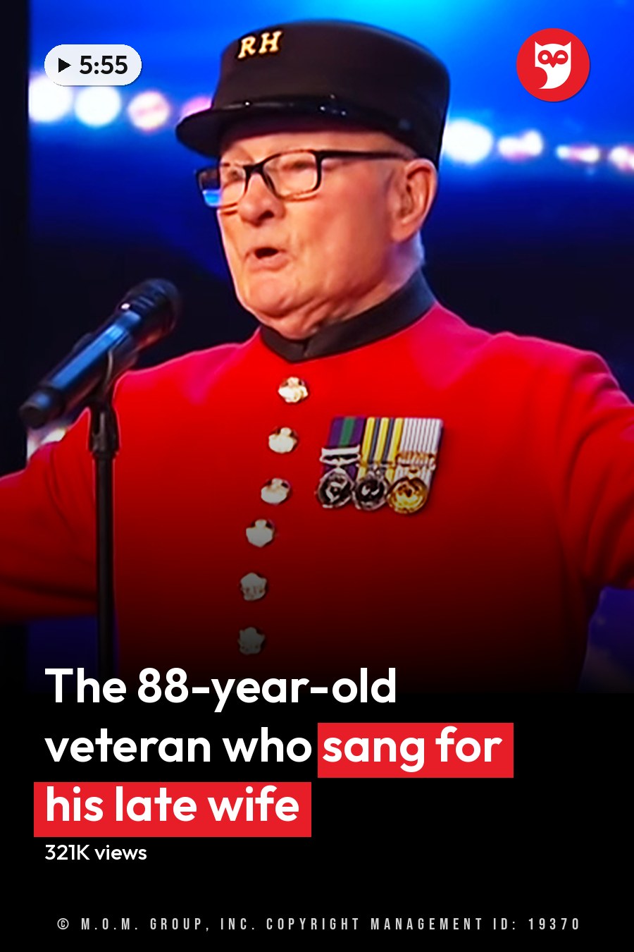 A male performer in a red military-style jacket adorned with medals, performing at an indoor stage event under bright lighting and colorful effects. The headline runs in white letters across the lower third.