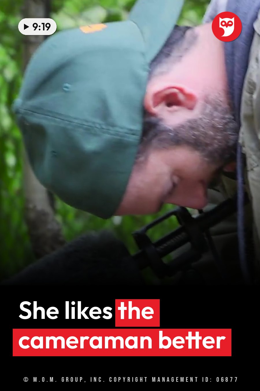 A man in a green cap leans forward and looks down near a black object with a furry top. A headline runs in white letters across the lower third.
