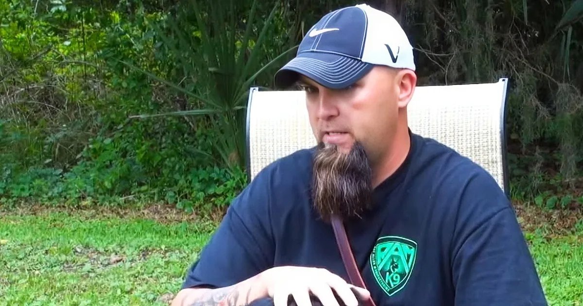 Adult male in a relaxed casual t-shirt with 'RAT 19' logo and white Nike cap, sitting outdoors on green grassy terrain with white woven chair visible behind him.
