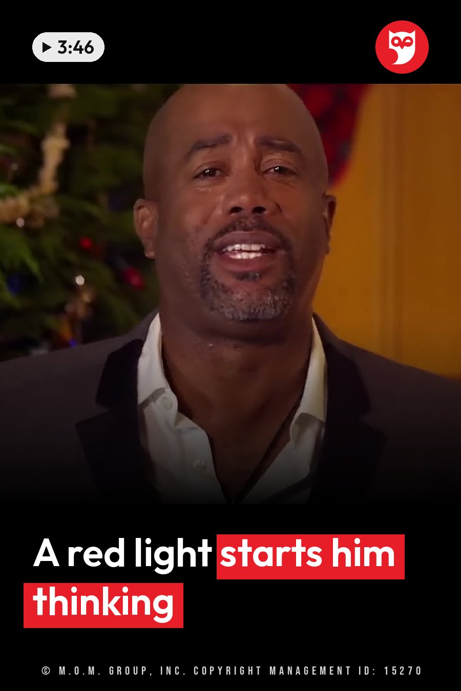 A bald man with a goatee smiles, wearing a dark jacket over a white shirt beside a decorated tree. A headline runs in white letters across the lower third.