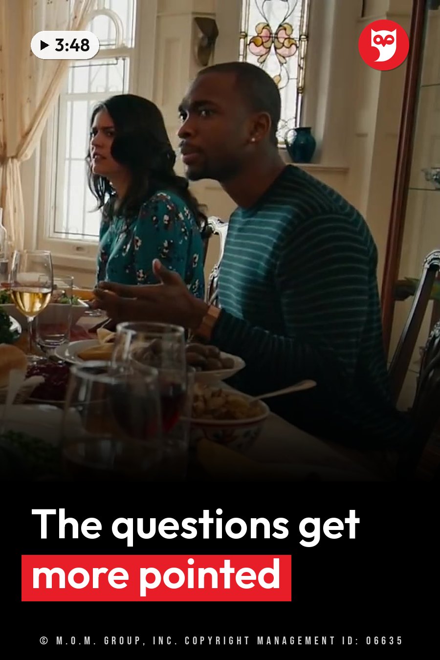 Two people sit at a dining table with food and drinks, both looking at something off camera. A headline runs in white letters across the lower third.