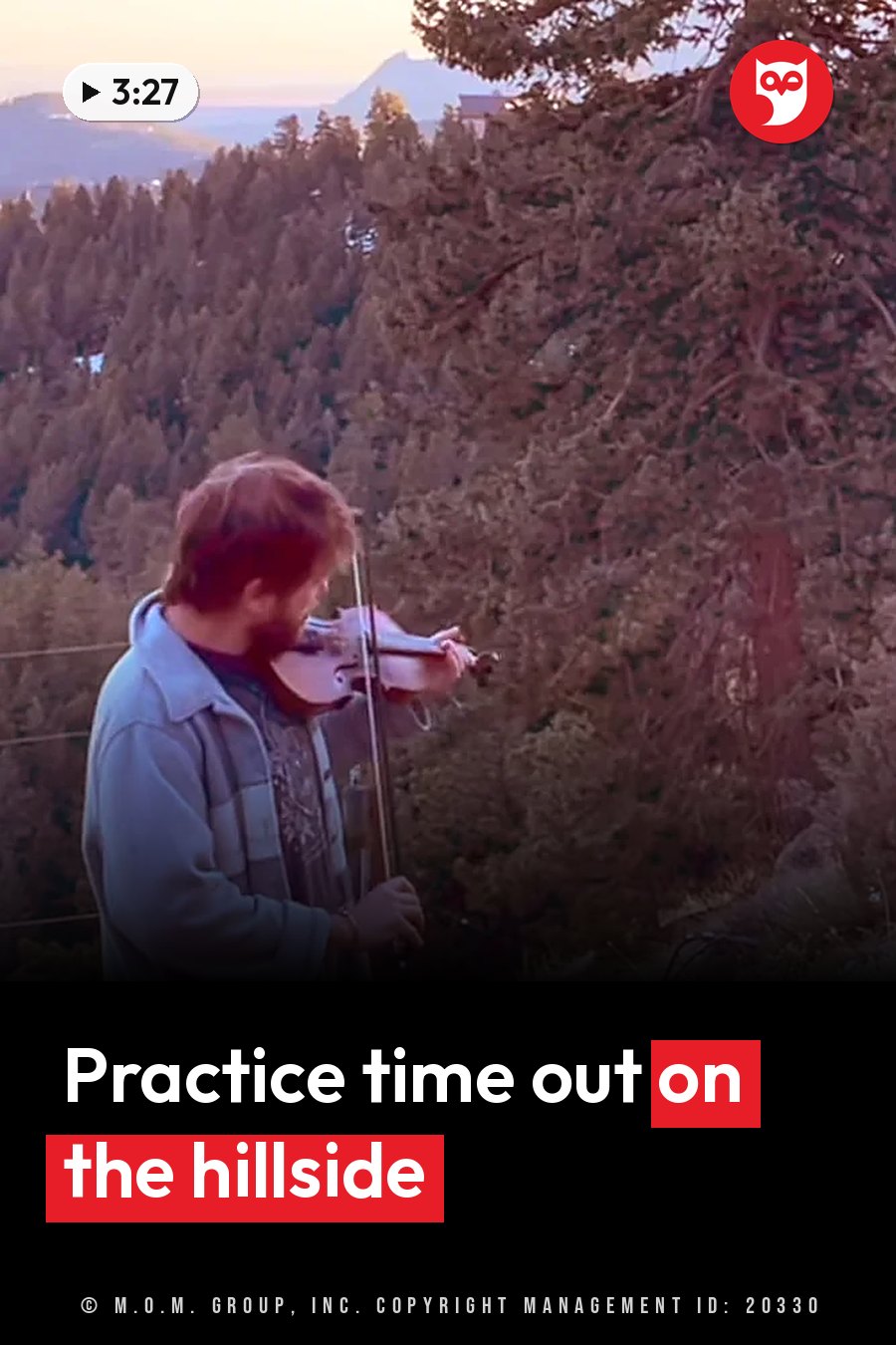 A man plays a violin outdoors near trees, with mountains in the distance at sunset. A headline runs in white letters across the lower third.