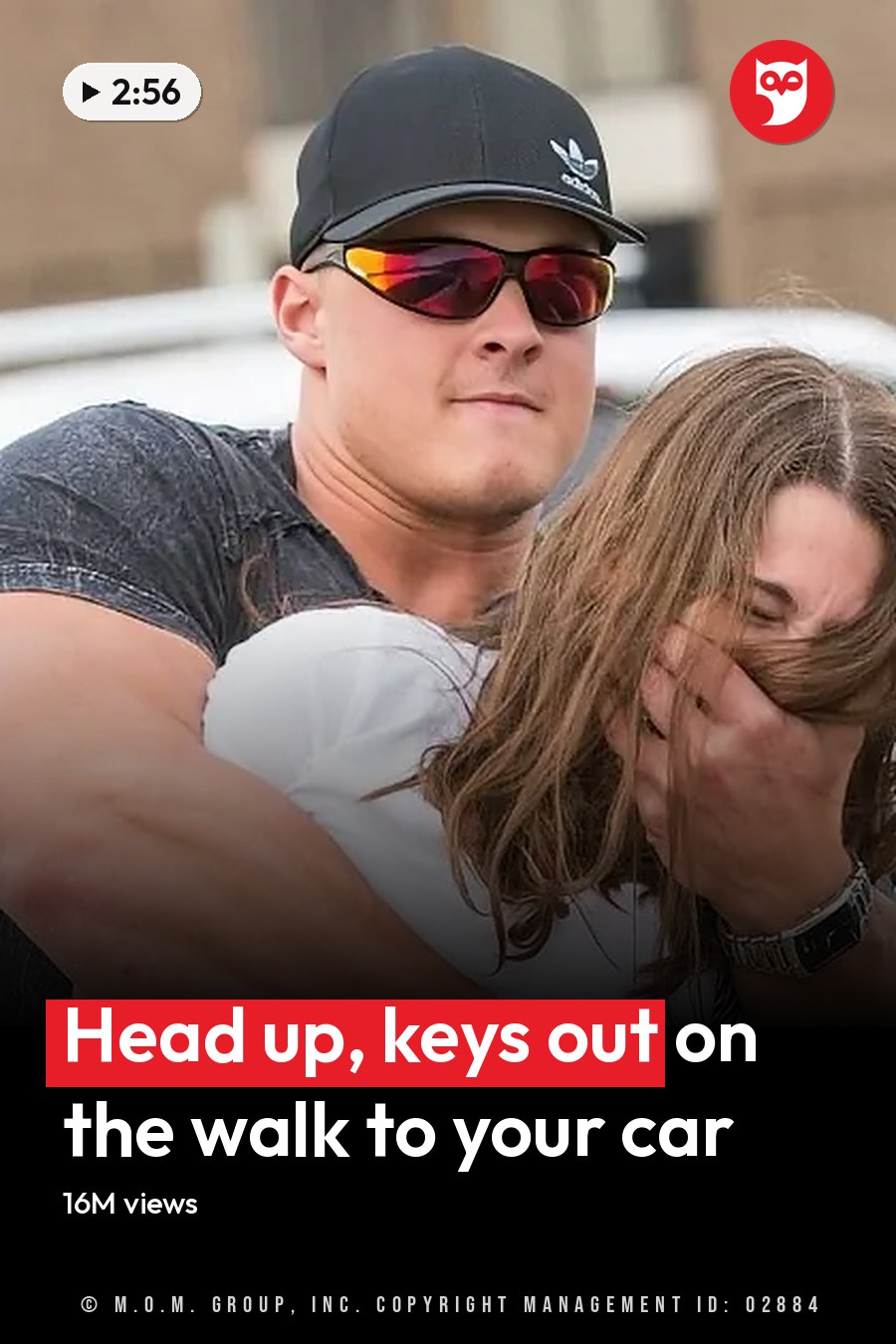 A muscular man in a cap and sunglasses carries a woman covering her face through a parking lot. The headline runs in white letters across the lower third.